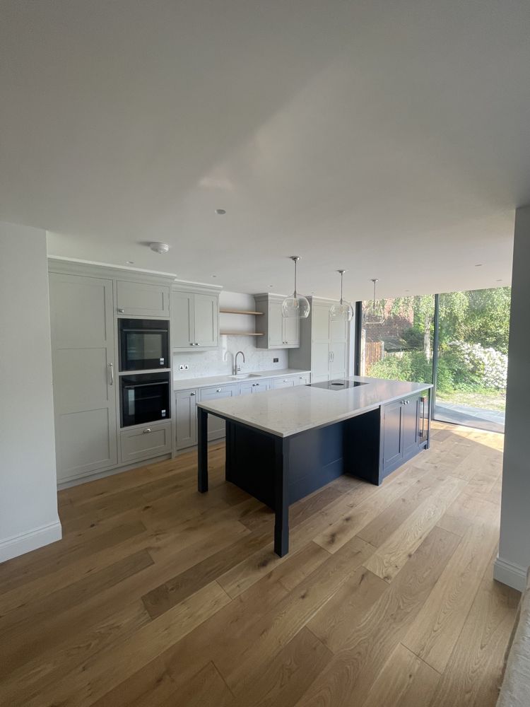 Open-plan kitchen with shaker units, built-in ovens and a navy island with white worktop